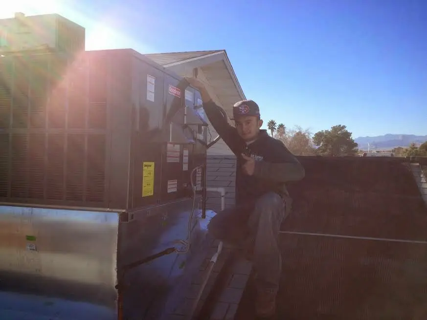 HVAC technician performing Air Duct Repair on a rooftop unit in Sand Springs